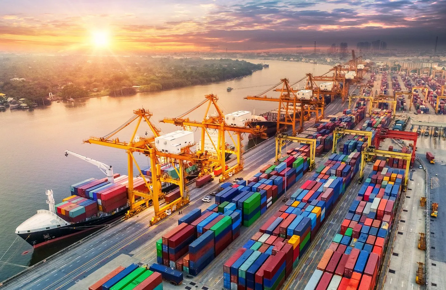 Un porto commerciale con gru e container al tramonto