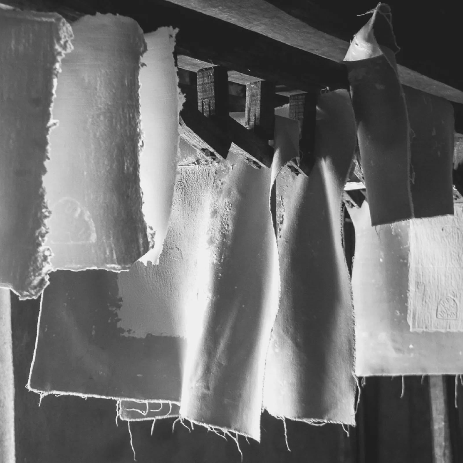 Fogli appesi ad asciugare in un vecchio opificio, fotografia in bianco e nero